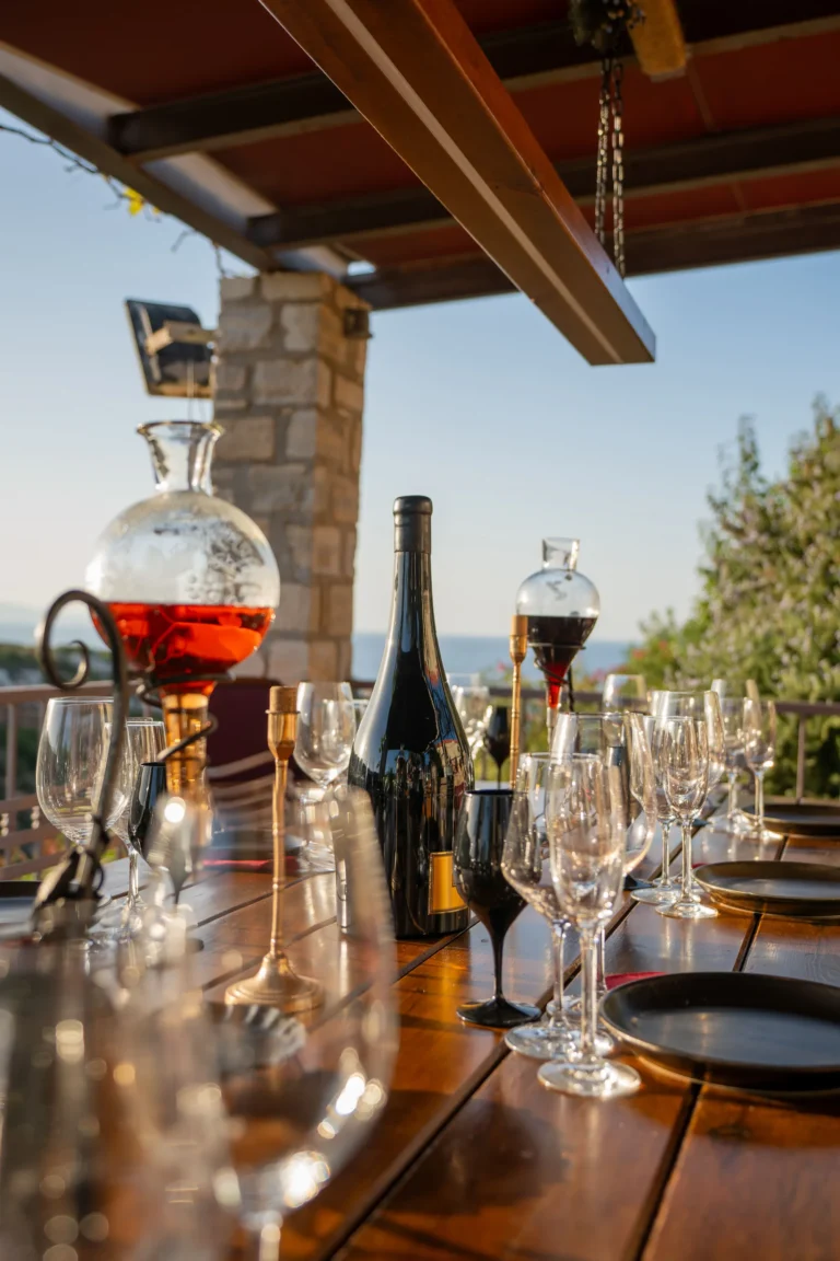 Table set up for wine tasting with glasses and a bottle, looking out over the sea and gorge.