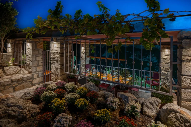 Wine tasting balcony in Rethymno at night with flowers and wine vines.