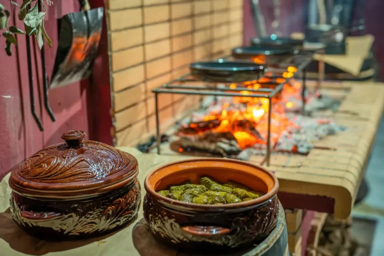 Clay pot with Dolmades: vine leaves stuffed with rice and herbs. A traditional Cretan dish with a stone grill in the background.