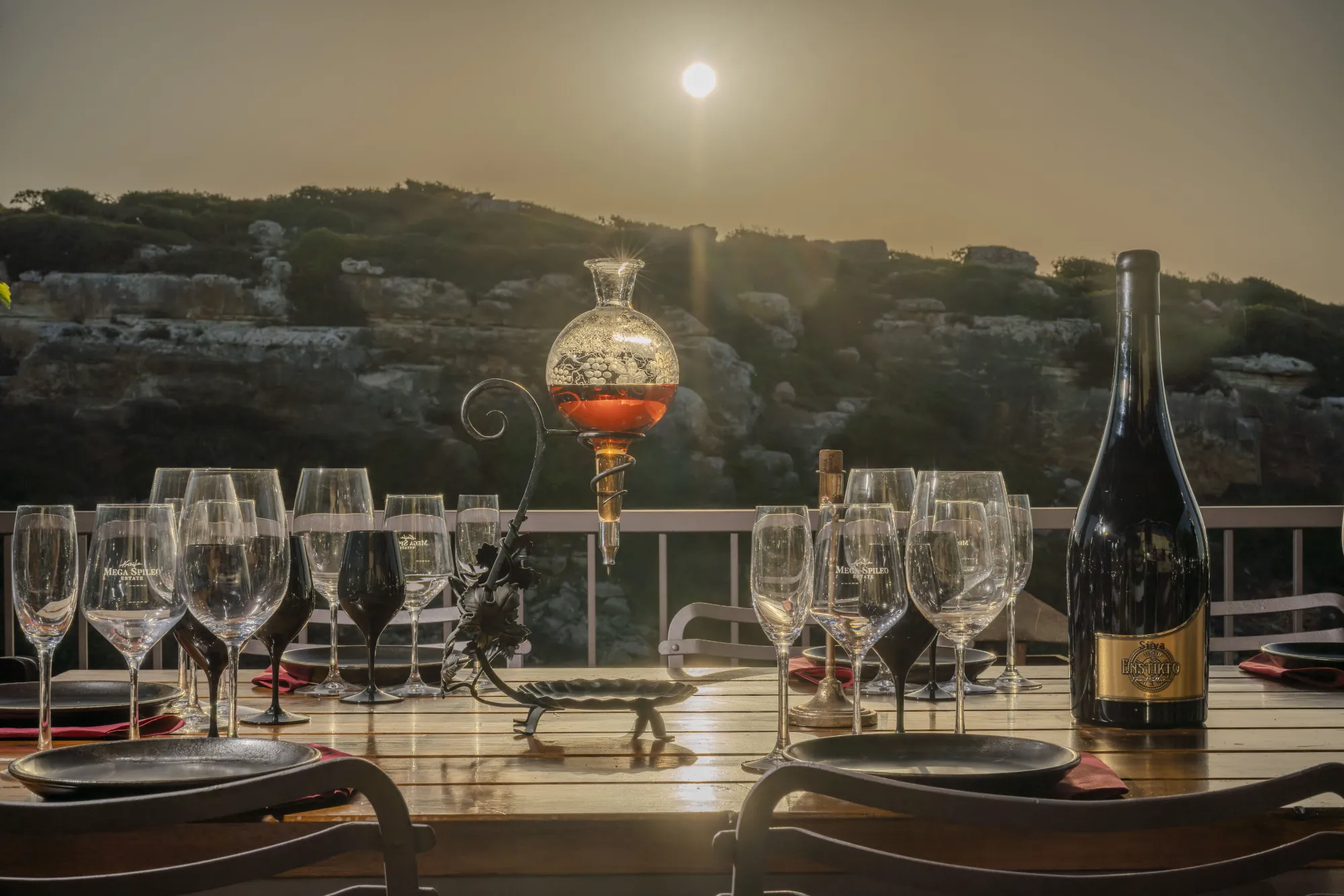 Wine tasting table with glasses, wine bottle and wine distributor with a gorge and sunset view.